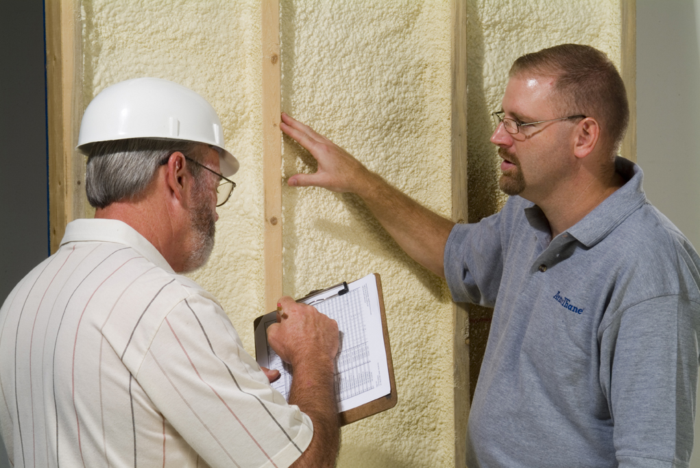 Spray foam contractor reviewing an insulated wall with a homeowner