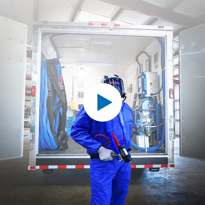 Spray foam applicator standing in front of an equipped spray rig